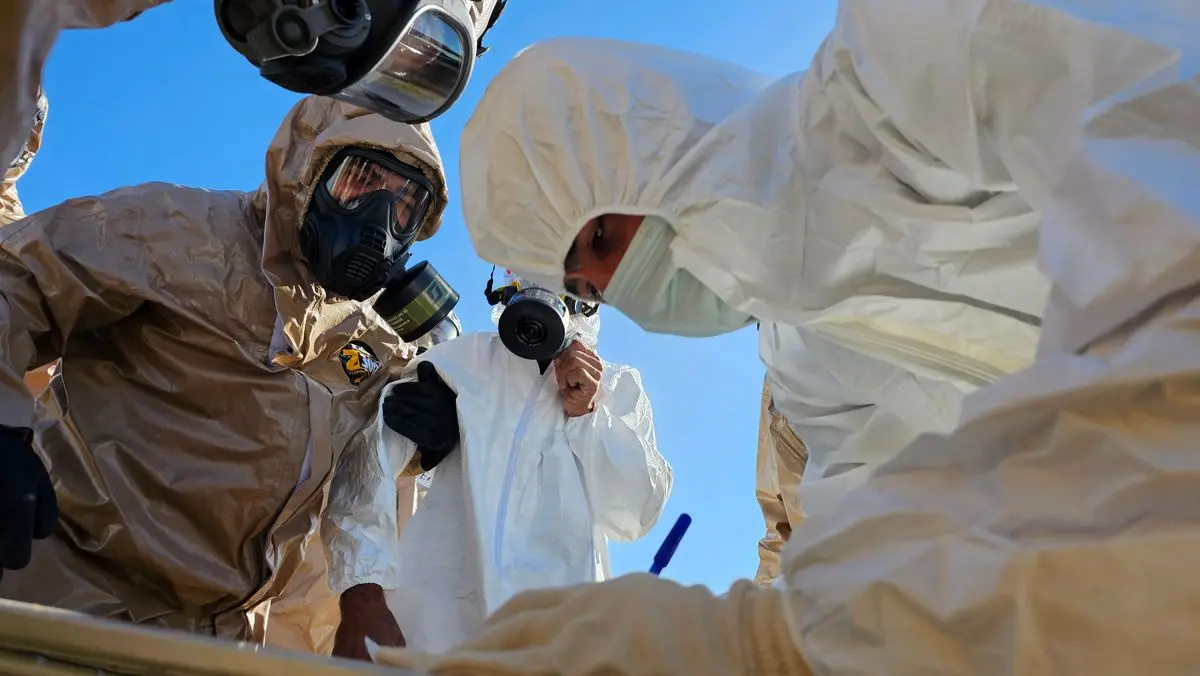 Two technicians in white suits and respirators during an inspection.