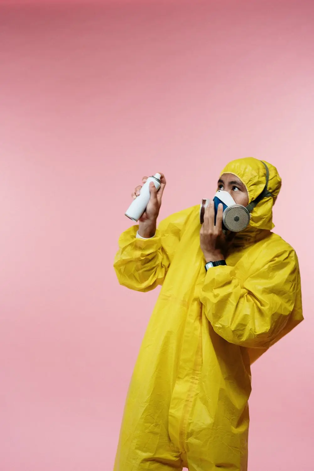 A technician in a yellow suit and respirator with a spray can.
